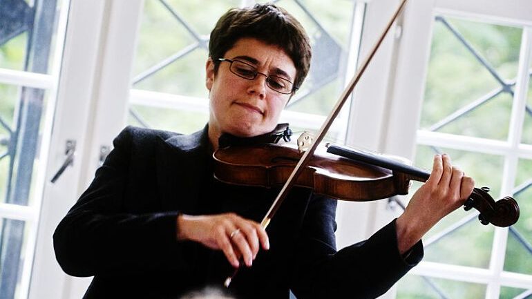 Kvinnelig fiolinist med brunt hår og dress